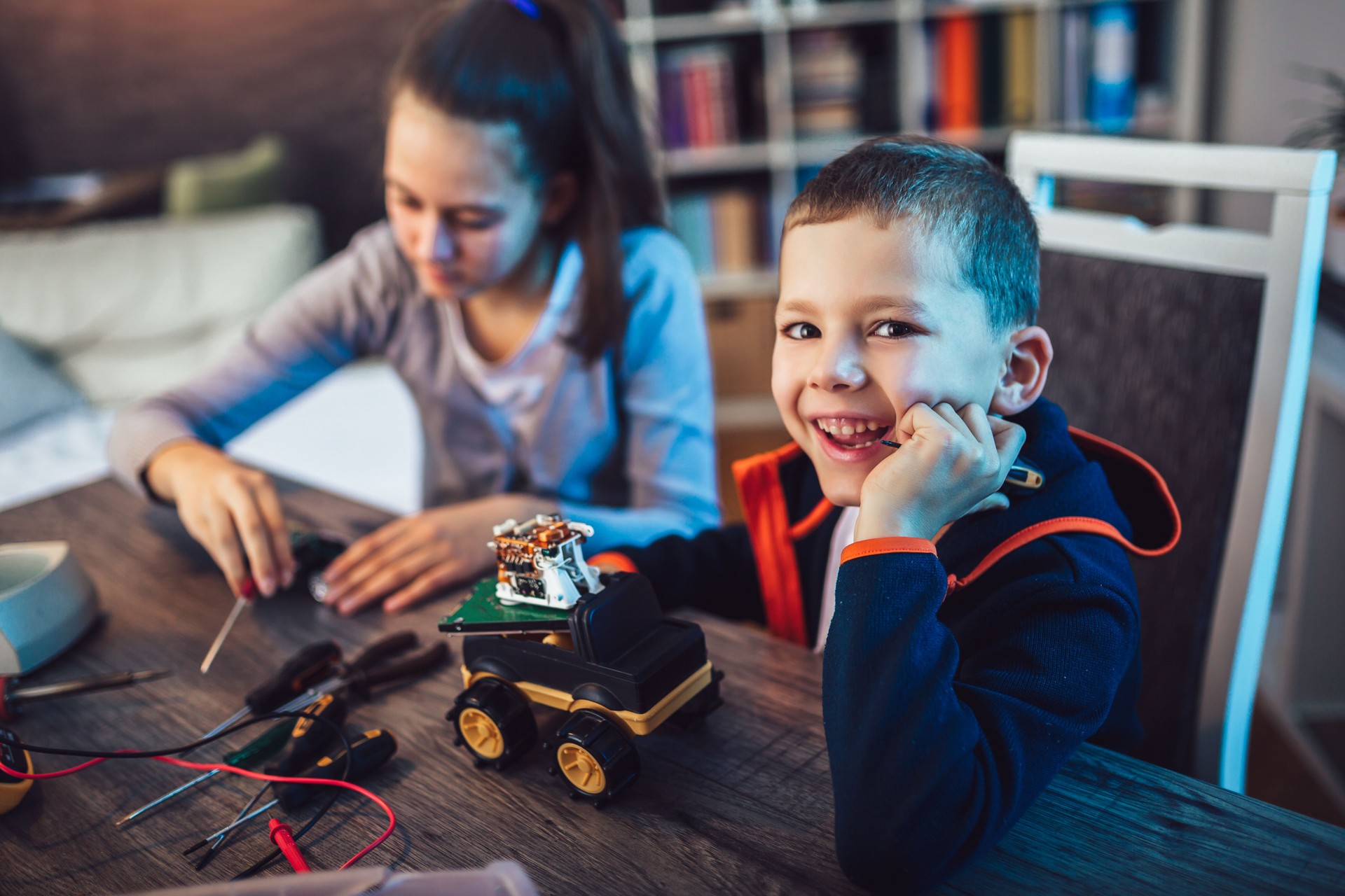 Happy smiling boy and girl constructs technical toy. Technical toy on table full of details
